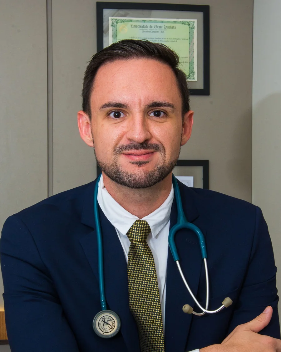 Dr. Caio Bitencourt em seu consultório, com diploma da Unoeste ao fundo